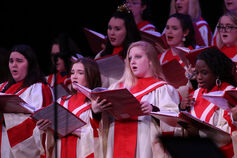 A group of choir members perform on stage.